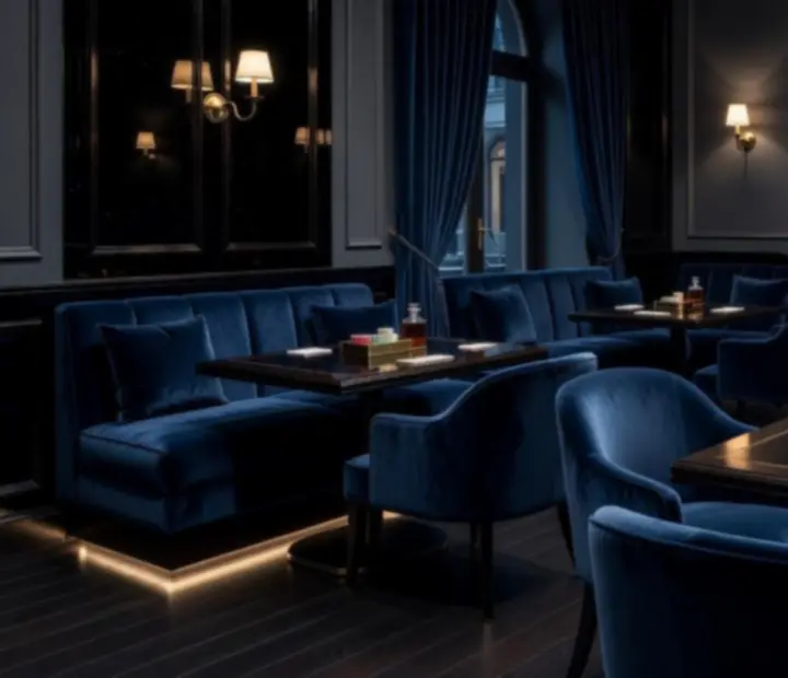 Kameralny, ciemny lounge z aksamitnymi fotelami i stołem do gier